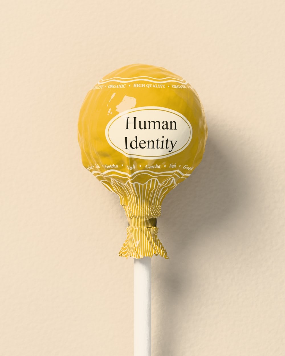 The finished lollipop wrapped in crinkled gold plastic, twisted at the neck, with a cream oval label reading Human Identity.